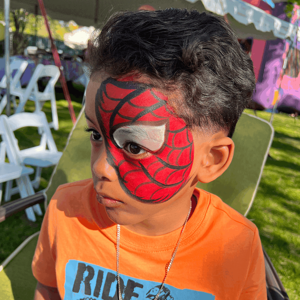 Niño con carita pintada de Spiderman en evento infantil al aire libre