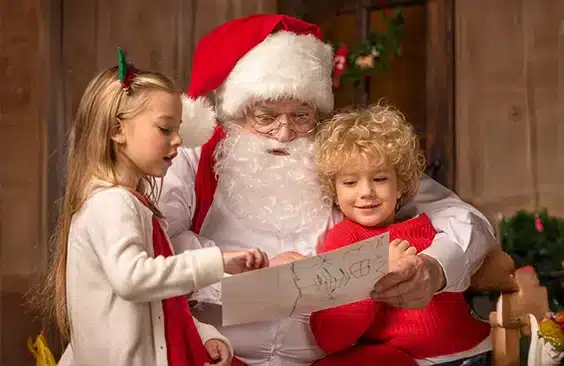 Santa Claus con barba real haciendo entrega de regalos durante una Visita de Santa