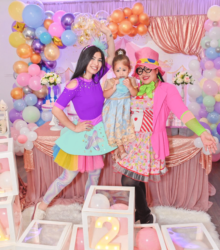 Se verían a dos Payasos Infantiles alegrando el cumpleaños de una bebe, están posando para una fotografía en un cumpleaños infantil.
