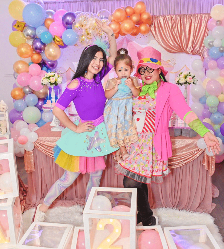 Se verían a dos Payasos Infantiles alegrando el cumpleaños de una bebe, están posando para una fotografía en un cumpleaños infantil.